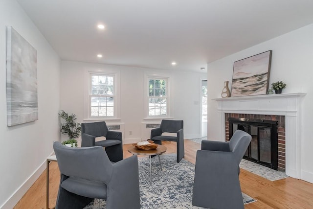 living room with a brick fireplace, recessed lighting, wood finished floors, and baseboards