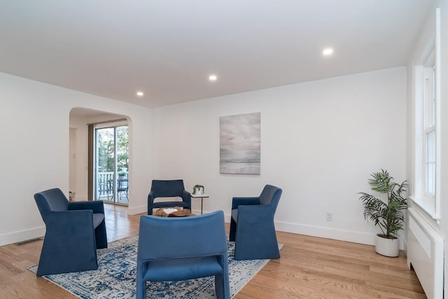 sitting room with arched walkways, visible vents, baseboards, and light wood-style floors