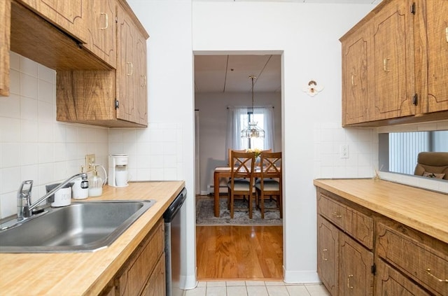 kitchen featuring a baseboard radiator, a sink, dishwasher, tasteful backsplash, and brown cabinets