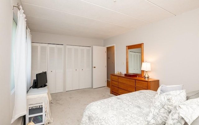 bedroom with multiple closets and light colored carpet