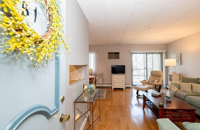 living room with a baseboard heating unit, a healthy amount of sunlight, wood finished floors, and a baseboard radiator