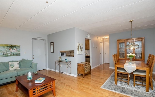 living area featuring light wood-type flooring, baseboards, and an inviting chandelier