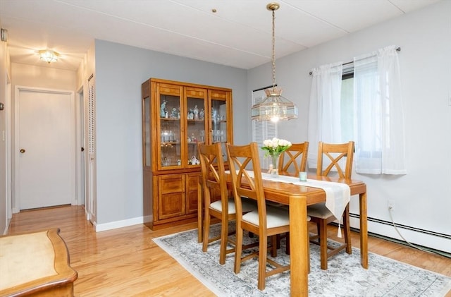 dining room with light wood finished floors, baseboard heating, and baseboards