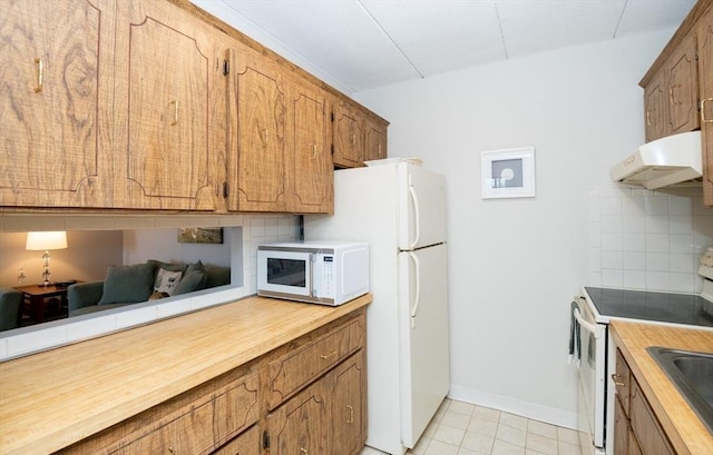 kitchen with decorative backsplash, white appliances, brown cabinets, and under cabinet range hood