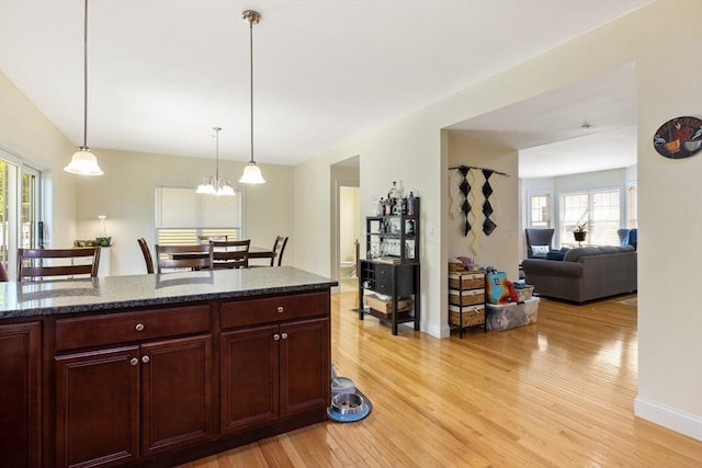 6 Comanche Ter Unit 6, Westford, MA 01886 - kitchen featuring light wood finished floors, dark brown cabinets, decorative light fixtures, dark stone countertops, and a chandelier