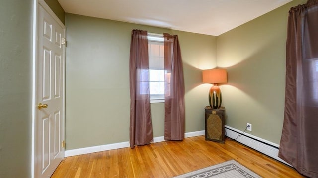 unfurnished bedroom with a baseboard radiator and light wood-type flooring