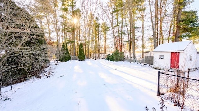 snowy yard featuring a shed