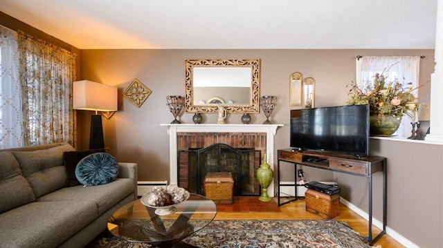 sitting room featuring wood-type flooring, a baseboard heating unit, and a fireplace