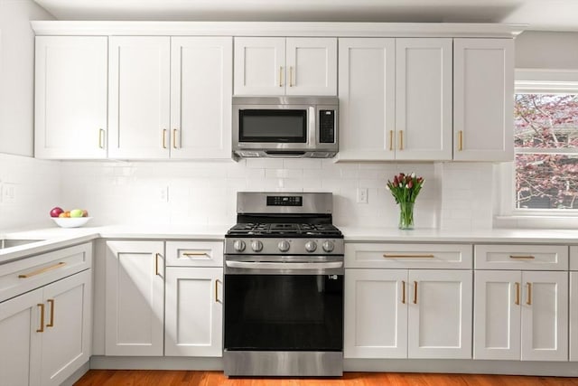 301 Pond St, Boston, MA 02130 - kitchen with appliances with stainless steel finishes, light countertops, decorative backsplash, and white cabinetry