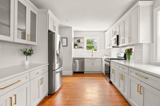 301 Pond St, Boston, MA 02130 - kitchen with stainless steel appliances, open shelves, light wood finished floors, tasteful backsplash, and white cabinets