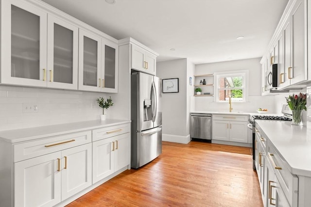 301 Pond St, Boston, MA 02130 - kitchen with stainless steel appliances, open shelves, light countertops, light wood finished floors, and backsplash
