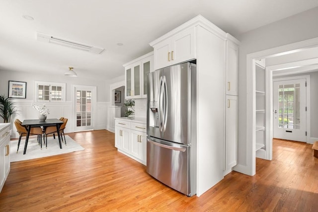 301 Pond St, Boston, MA 02130 - kitchen with stainless steel fridge, glass insert cabinets, white cabinets, light wood-style floors, and light countertops