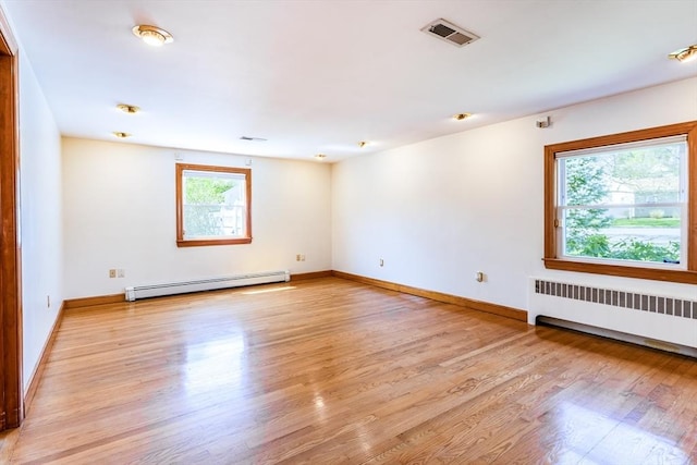unfurnished room featuring baseboard heating, light wood-style floors, radiator, baseboards, and visible vents