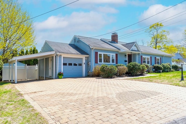 single story home featuring an attached garage, an attached carport, a gate, a chimney, and decorative driveway