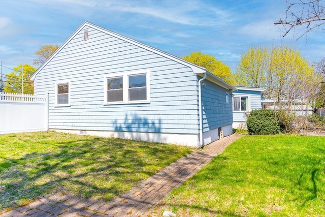 view of side of home with a lawn and fence