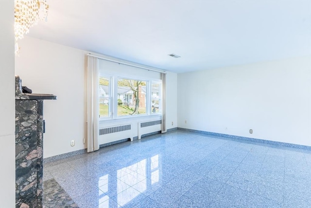 unfurnished living room featuring baseboards, radiator, and visible vents