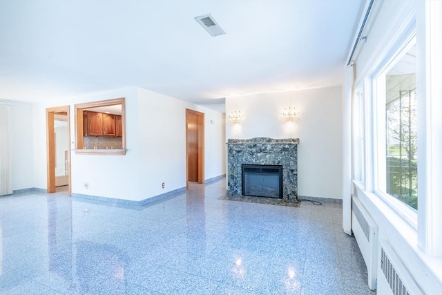 unfurnished living room featuring baseboards, visible vents, and a fireplace with flush hearth
