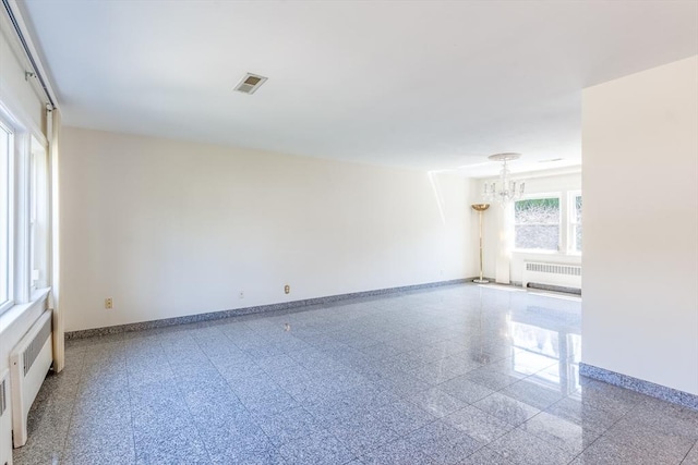 unfurnished room featuring visible vents, baseboards, radiator heating unit, and a chandelier