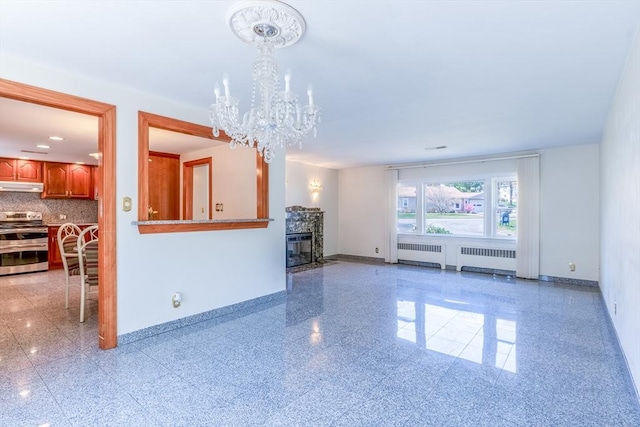 unfurnished living room with baseboards, radiator, a chandelier, and granite finish floor