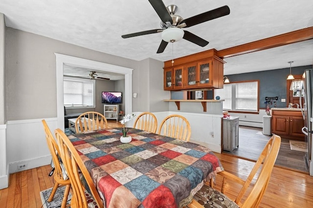 dining area featuring light wood-style floors, ceiling fan, and a baseboard heating unit