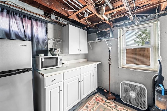 interior space with freestanding refrigerator, light countertops, white cabinets, and white microwave