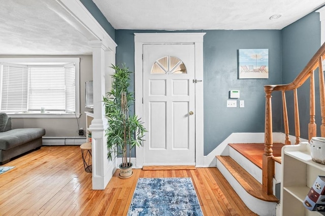 foyer with stairway, a baseboard radiator, baseboards, and hardwood / wood-style floors
