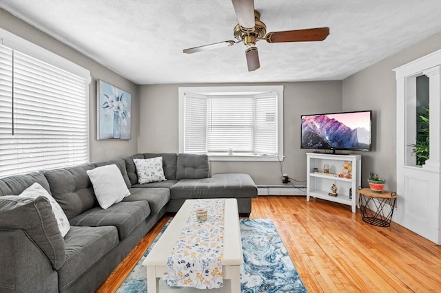 living area featuring baseboard heating, ceiling fan, and wood finished floors