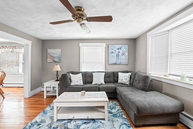 living area featuring baseboards, baseboard heating, and wood finished floors