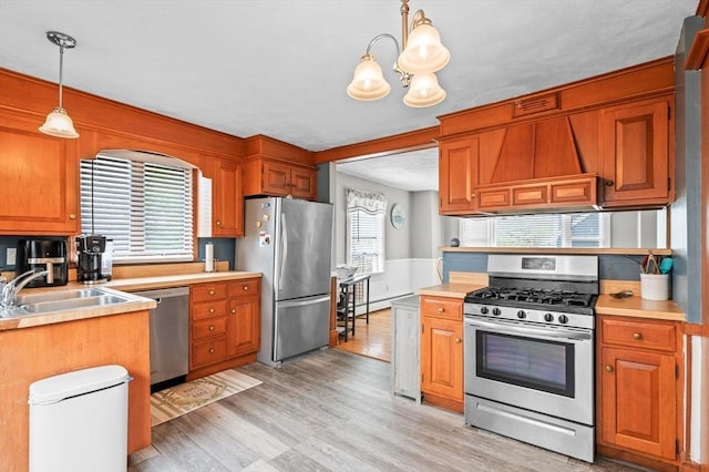 kitchen with hanging light fixtures, a sink, light wood-style floors, light countertops, and appliances with stainless steel finishes