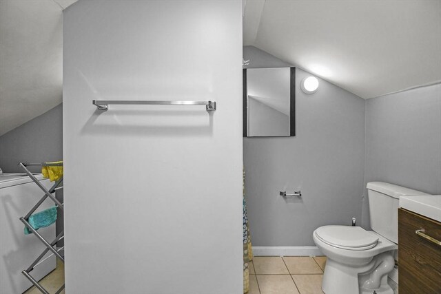 bathroom with vanity, tile patterned floors, washer / dryer, toilet, and lofted ceiling