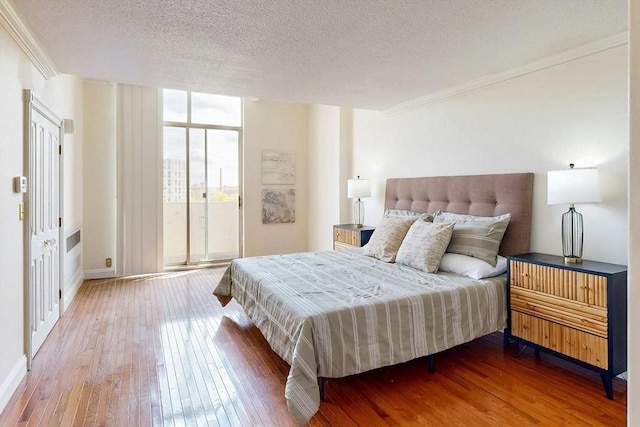33 Pond Ave Unit Ph1207, Brookline, MA 02445 - bedroom featuring hardwood / wood-style flooring, ornamental molding, a textured ceiling, baseboards, and a wall of windows