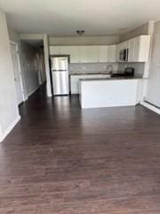620 Dudley St, Boston, MA 02125 - kitchen featuring white cabinets, stainless steel microwave, a peninsula, and baseboard heating