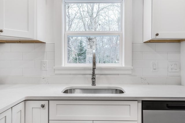 kitchen featuring white cabinets, sink, backsplash, and stainless steel dishwasher