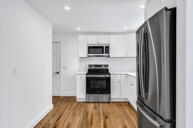 kitchen featuring appliances with stainless steel finishes, decorative backsplash, white cabinets, and light hardwood / wood-style flooring