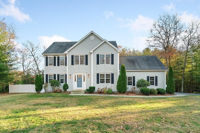 colonial-style house featuring fence and a front lawn