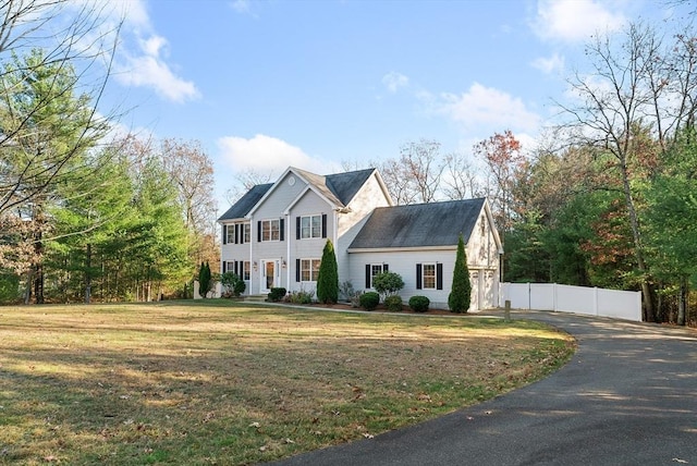 view of front facade with aphalt driveway, a front yard, and fence