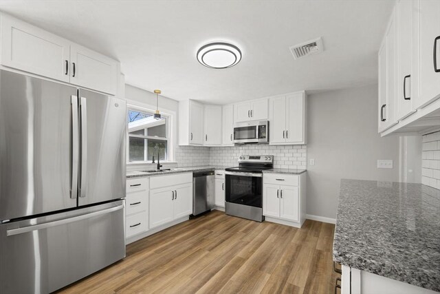 73 Mckinley Ave, Ludlow, MA 01056 - kitchen with visible vents, decorative backsplash, a sink, dark stone countertops, and stainless steel appliances