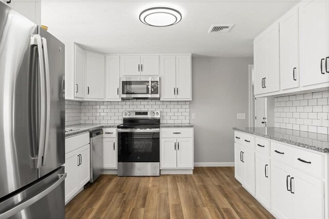 73 Mckinley Ave, Ludlow, MA 01056 - kitchen with visible vents, wood finished floors, white cabinetry, tasteful backsplash, and appliances with stainless steel finishes