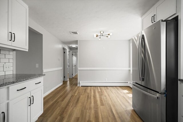 73 Mckinley Ave, Ludlow, MA 01056 - kitchen with freestanding refrigerator, dark stone counters, wood finished floors, a baseboard radiator, and visible vents
