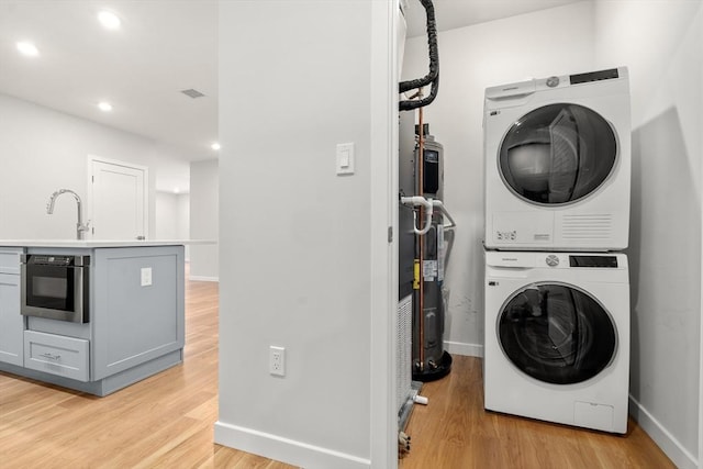 267 Old Colony Unit 205, Boston, MA 02127 - clothes washing area featuring a sink, light wood-style floors, stacked washer / dryer, and laundry area
