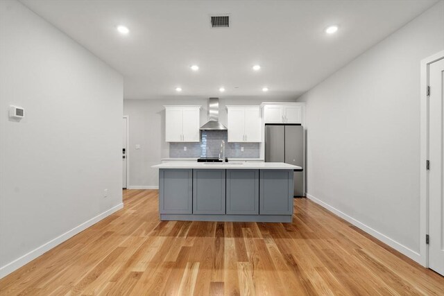267 Old Colony Unit 205, Boston, MA 02127 - kitchen featuring visible vents, white cabinets, wall chimney exhaust hood, freestanding refrigerator, and a center island with sink