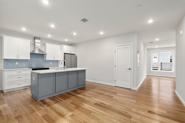 267 Old Colony Unit 205, Boston, MA 02127 - kitchen with white cabinetry, freestanding refrigerator, a center island with sink, visible vents, and wall chimney exhaust hood