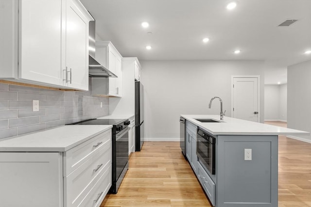 267 Old Colony Unit 205, Boston, MA 02127 - kitchen with baseboards, white cabinetry, wall chimney exhaust hood, appliances with stainless steel finishes, and a sink