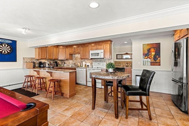 kitchen featuring white appliances, baseboard heating, a kitchen bar, decorative backsplash, and kitchen peninsula