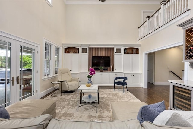 living room with french doors, crown molding, dark hardwood / wood-style flooring, a towering ceiling, and beverage cooler