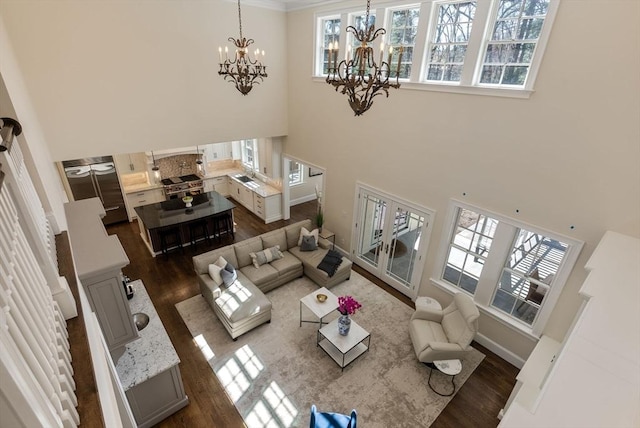 living room with dark wood-type flooring, sink, a high ceiling, and a notable chandelier