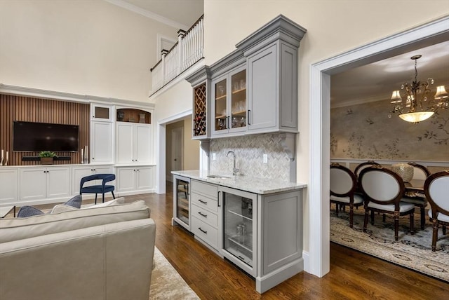 kitchen featuring sink, crown molding, light stone countertops, and beverage cooler