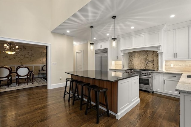 kitchen featuring hanging light fixtures, a center island, high quality appliances, light stone counters, and white cabinets