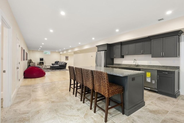 kitchen with sink, stainless steel refrigerator, dishwashing machine, gray cabinets, and a kitchen island