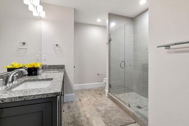 bathroom featuring vanity, toilet, and a shower with door